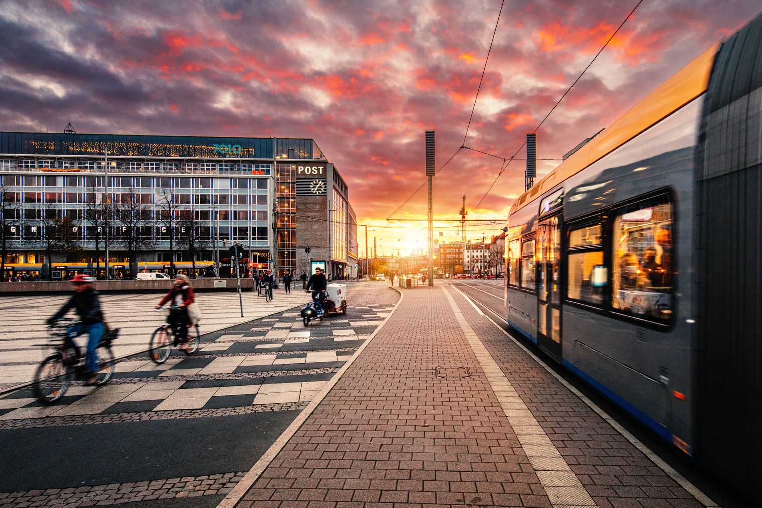 Tagung & Konferenz Leipzig Convention: Tagungshotel Felix Suiten am Augustusplatz bei Sonnenuntergang mit Fahrradfahrern und Straßenbahn